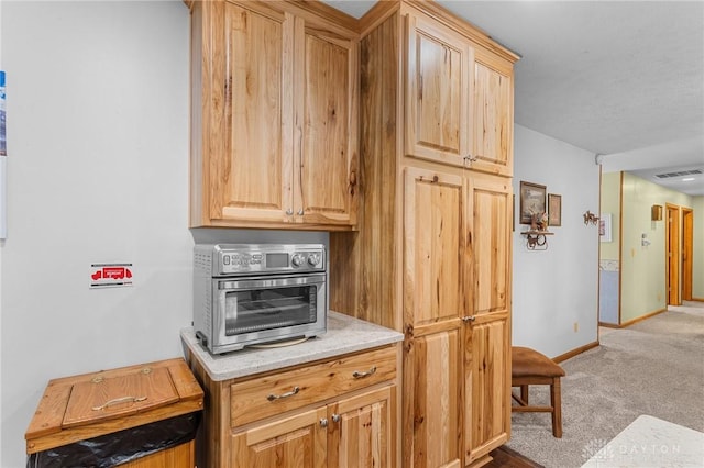 kitchen featuring visible vents, light colored carpet, light countertops, baseboards, and a toaster