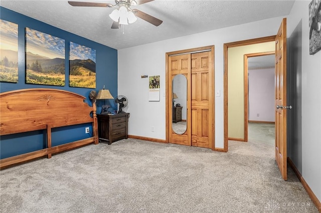 bedroom with a closet, a ceiling fan, baseboards, a textured ceiling, and carpet flooring