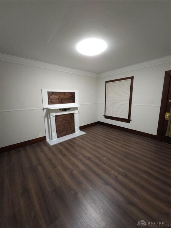 unfurnished living room with dark wood-style flooring, ornamental molding, and baseboards