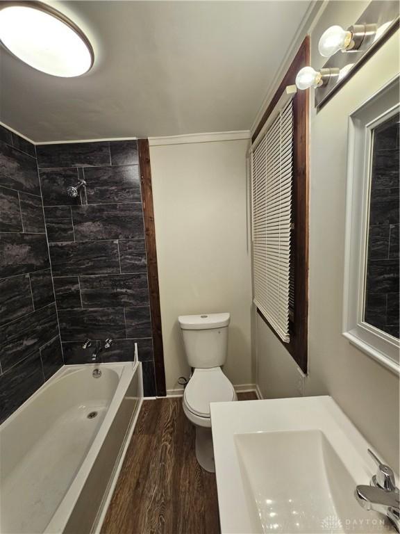 full bath with a sink, ornamental molding, toilet, shower / bathing tub combination, and wood finished floors