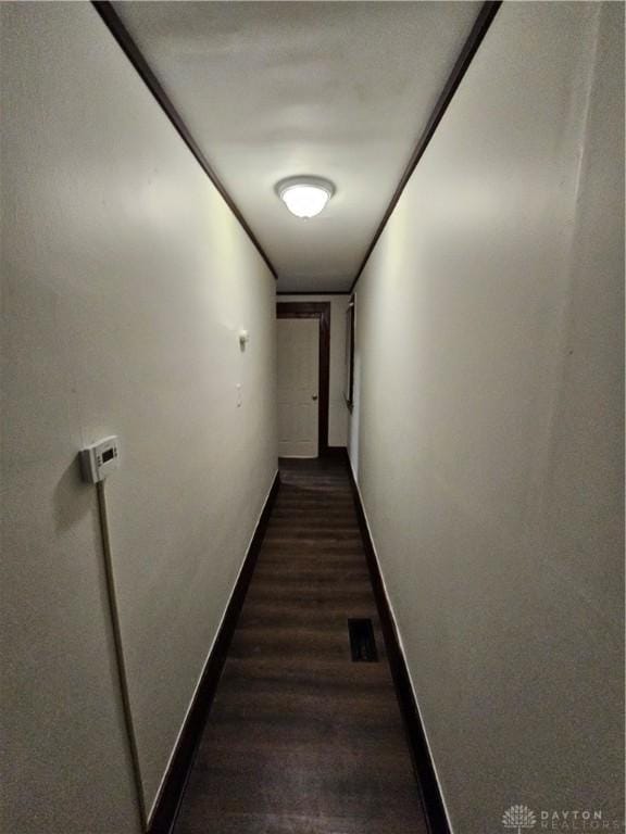 hallway with dark wood-style flooring and baseboards