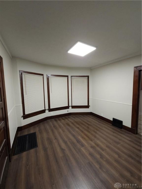 unfurnished room with baseboards and dark wood-style floors