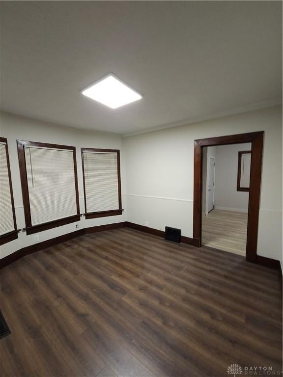 empty room with baseboards and dark wood-style floors