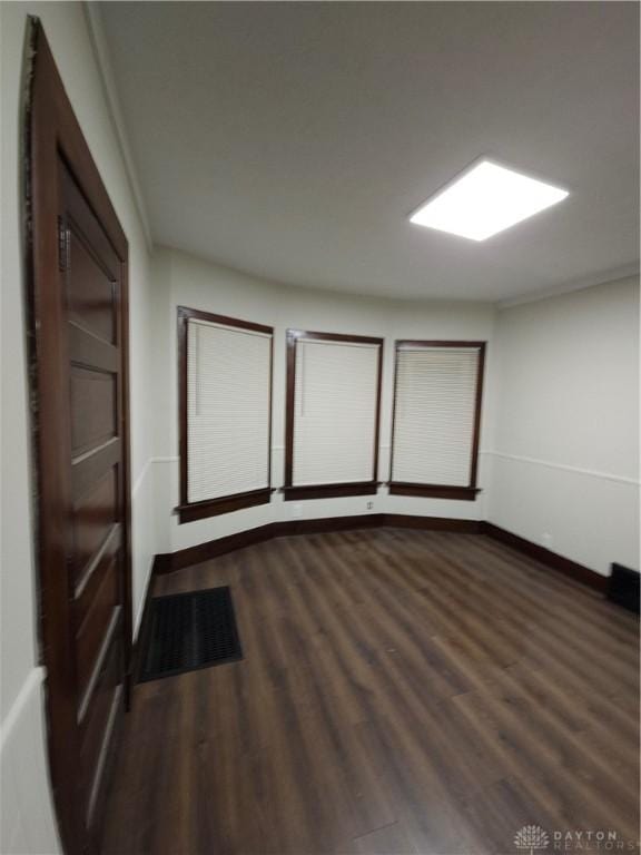 empty room featuring baseboards and dark wood finished floors
