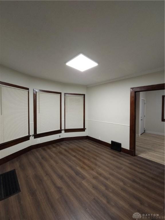 unfurnished room with visible vents, baseboards, and wood finished floors