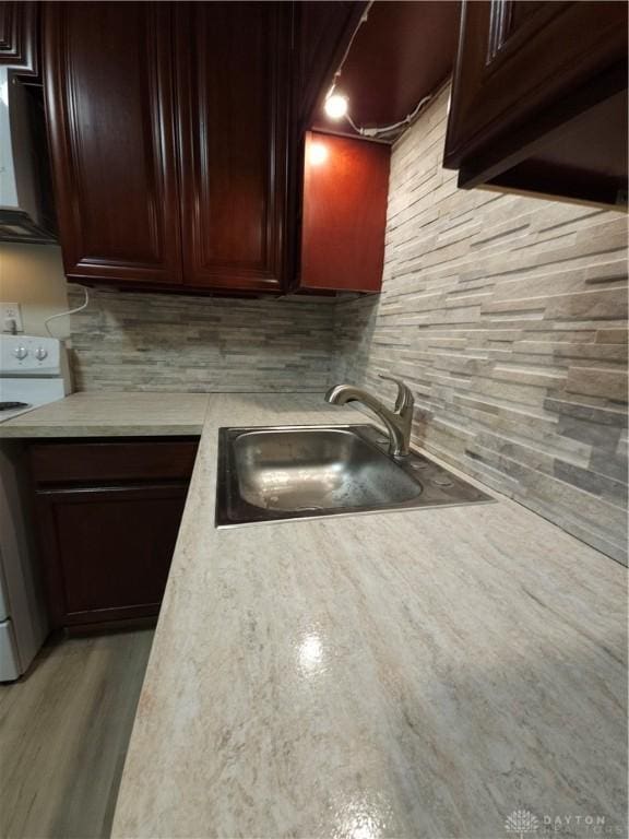 kitchen with light countertops, decorative backsplash, a sink, and white electric stove