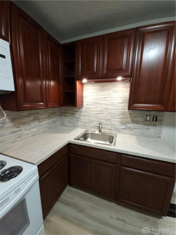 kitchen with a sink, light countertops, open shelves, and decorative backsplash