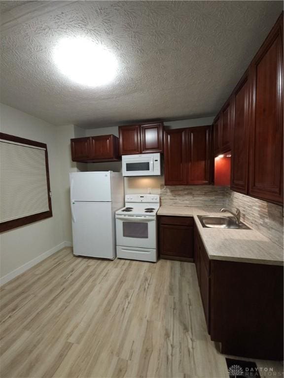 kitchen with a sink, light countertops, white appliances, light wood finished floors, and decorative backsplash