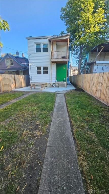 back of property with fence and a lawn