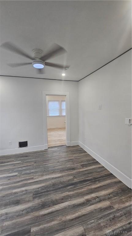 empty room featuring dark wood-style floors, baseboards, and a ceiling fan