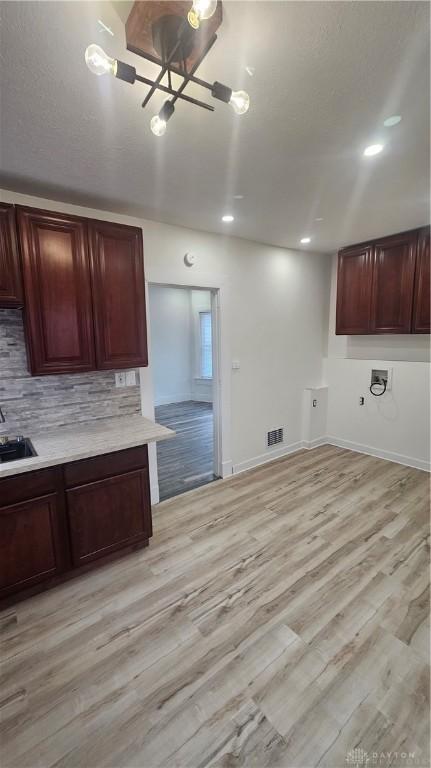kitchen with tasteful backsplash, visible vents, baseboards, light countertops, and light wood-style flooring