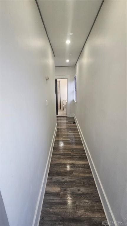 corridor with dark wood-type flooring, baseboards, and recessed lighting