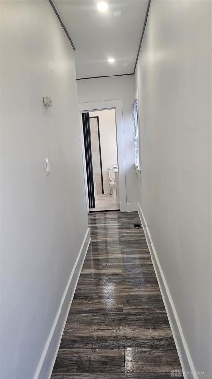 hallway featuring dark wood-type flooring and baseboards