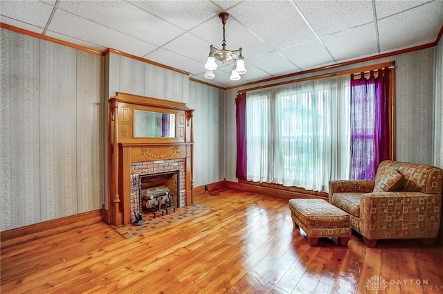 322 Hickory St, Dayton, OH 45410 - living area featuring a drop ceiling, a brick fireplace, hardwood / wood-style floors, and wallpapered walls