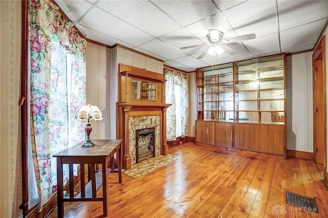 322 Hickory St, Dayton, OH 45410 - living room with visible vents, a drop ceiling, hardwood / wood-style floors, a stone fireplace, and ceiling fan