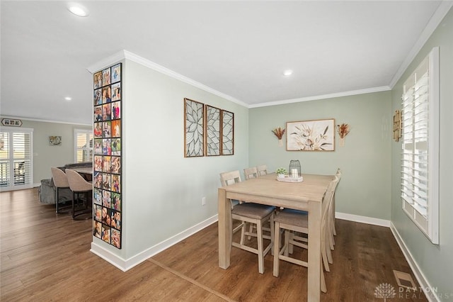 dining area featuring baseboards, ornamental molding, and wood finished floors