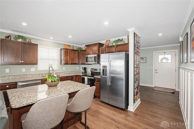 kitchen featuring stainless steel appliances, wood finished floors, a wealth of natural light, and crown molding
