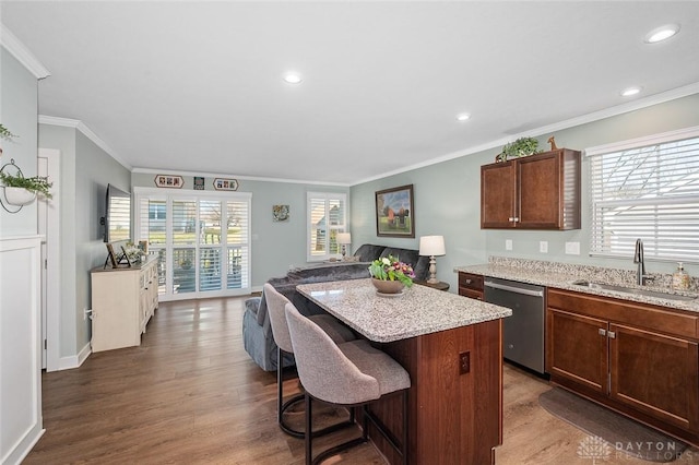kitchen featuring stainless steel dishwasher, wood finished floors, a sink, a kitchen bar, and ornamental molding