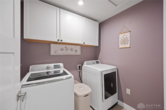 washroom featuring cabinet space and washer and clothes dryer