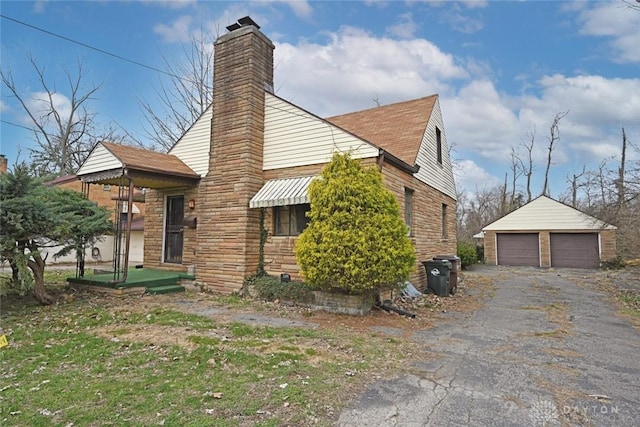 view of property exterior with an outbuilding, a chimney, and a detached garage