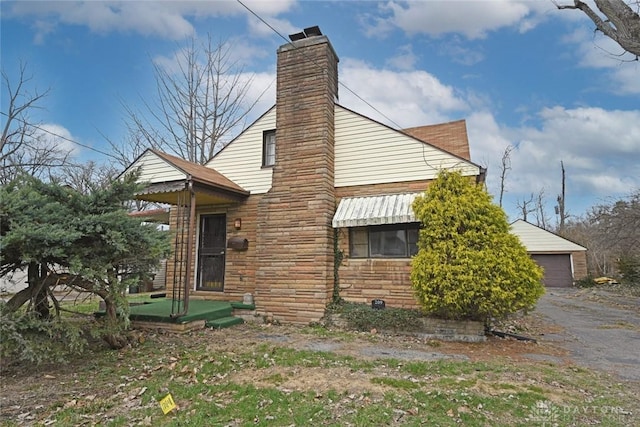 exterior space with a garage, stone siding, an outdoor structure, and a chimney