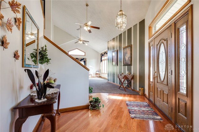 entryway with baseboards, wood finished floors, ceiling fan, and vaulted ceiling