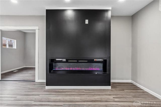room details with a glass covered fireplace, baseboards, and wood finished floors