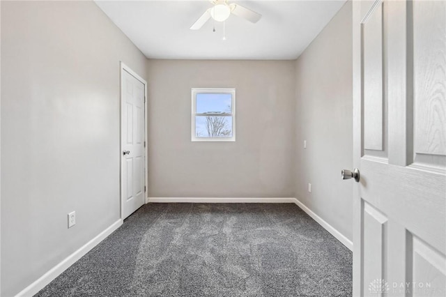 spare room featuring baseboards, dark colored carpet, and ceiling fan