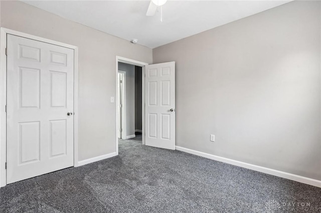 unfurnished bedroom featuring dark colored carpet, baseboards, and a ceiling fan