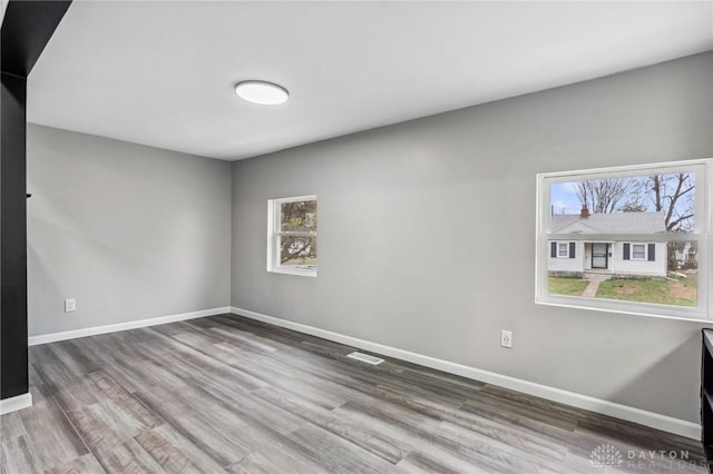 unfurnished room with visible vents, baseboards, and wood finished floors