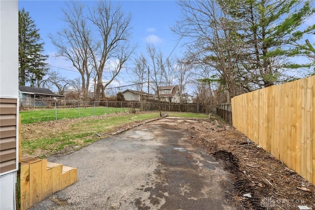 view of yard with a patio area, a fenced backyard, and driveway