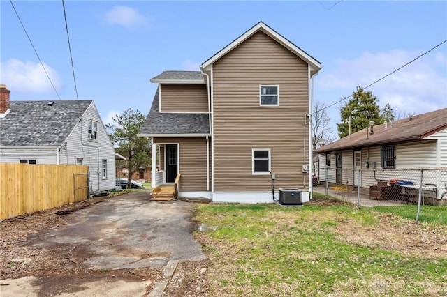 rear view of property featuring a patio, fence, roof with shingles, central AC, and entry steps