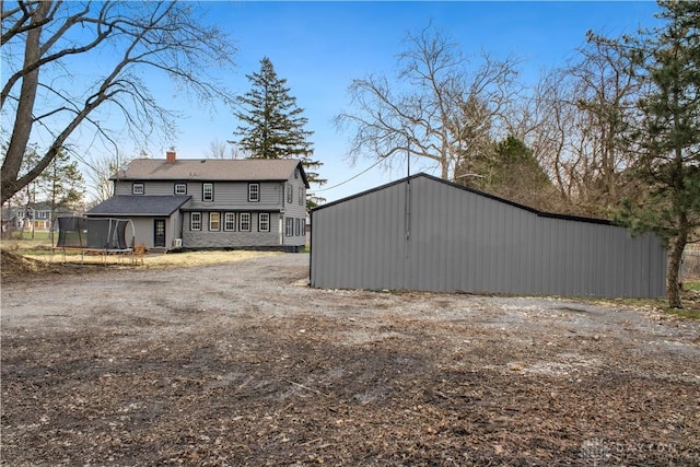4385 N Hyland Ave, Dayton, OH 45424 - back of property with an outbuilding, a chimney, and a trampoline