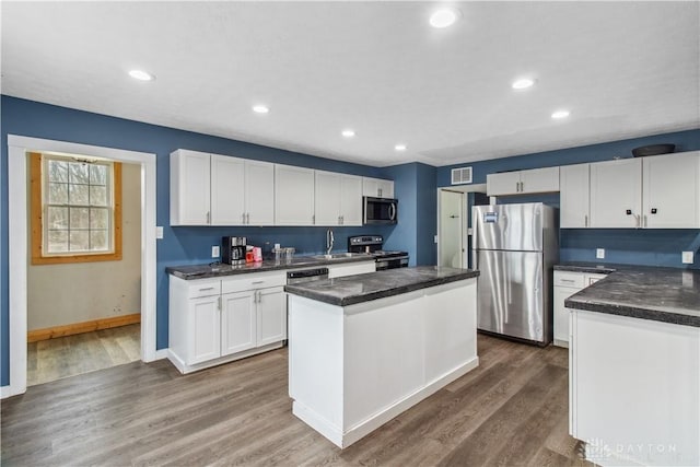 4385 N Hyland Ave, Dayton, OH 45424 - kitchen featuring wood finished floors, stainless steel appliances, white cabinets, dark countertops, and a center island