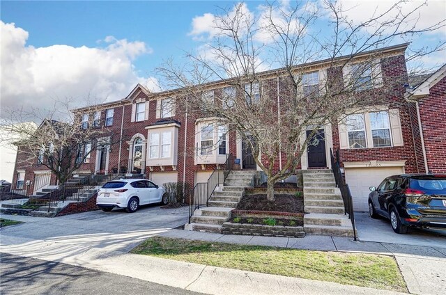 multi unit property with an attached garage, brick siding, and driveway
