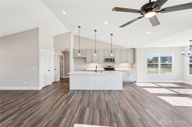 kitchen with decorative light fixtures, open floor plan, light countertops, appliances with stainless steel finishes, and wood finished floors