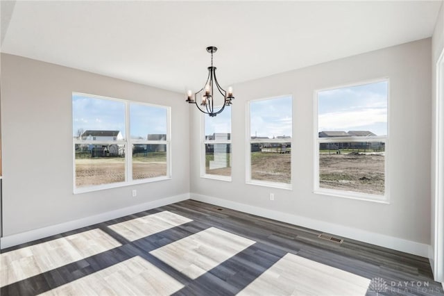 unfurnished dining area featuring visible vents, baseboards, a notable chandelier, and a healthy amount of sunlight
