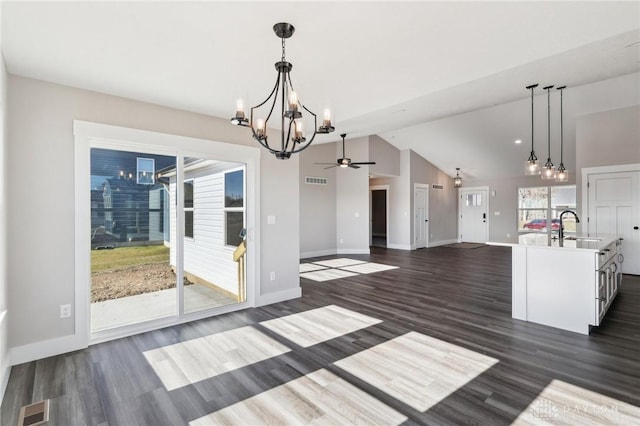 unfurnished dining area featuring visible vents, ceiling fan with notable chandelier, a sink, lofted ceiling, and dark wood-style flooring