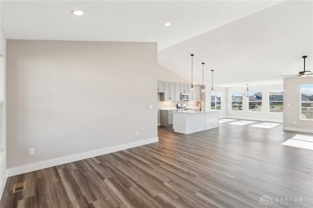 unfurnished living room featuring visible vents, baseboards, dark wood-type flooring, and vaulted ceiling