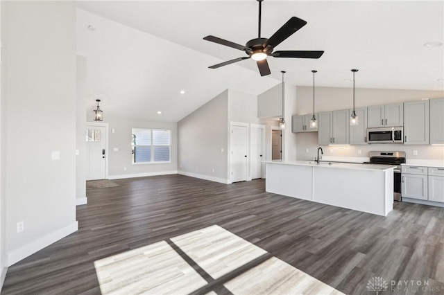 kitchen with a kitchen island with sink, gray cabinets, appliances with stainless steel finishes, a ceiling fan, and dark wood-style flooring