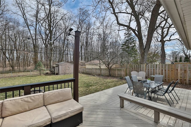 wooden terrace featuring outdoor lounge area, a fenced backyard, a yard, an outbuilding, and a storage unit