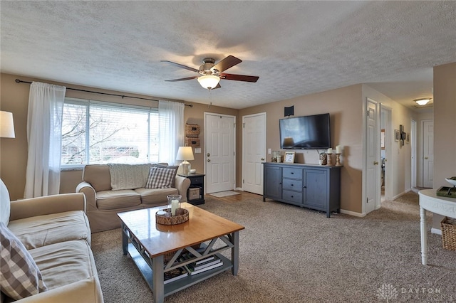 living area featuring light colored carpet, baseboards, a textured ceiling, and a ceiling fan