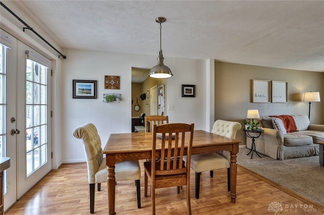 dining area featuring baseboards, light wood-type flooring, and a textured ceiling