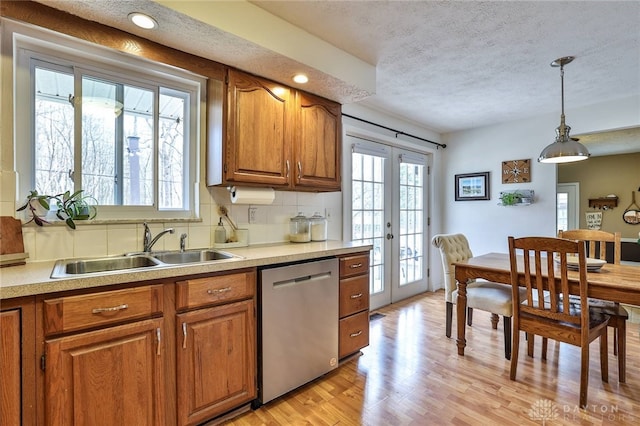 kitchen with dishwasher, brown cabinetry, french doors, and a sink