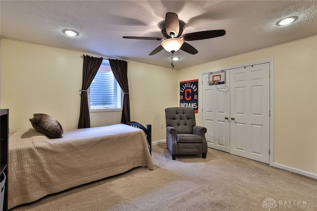 carpeted bedroom with a closet, baseboards, a textured ceiling, and ceiling fan