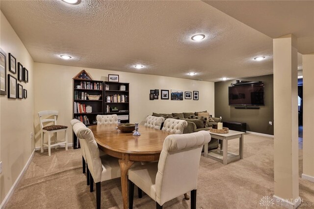 dining area featuring light colored carpet, baseboards, and a textured ceiling