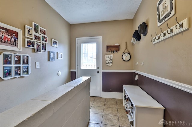 entryway with light tile patterned flooring and a textured ceiling
