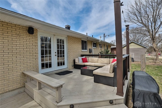wooden terrace with an outdoor living space, area for grilling, and french doors