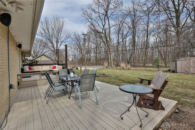 wooden terrace with a yard, outdoor dining space, a storage shed, and an outdoor structure