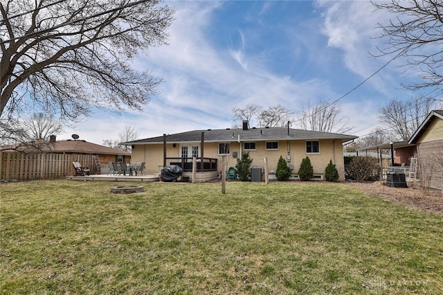 back of house featuring an outdoor fire pit, fence, a lawn, and a wooden deck